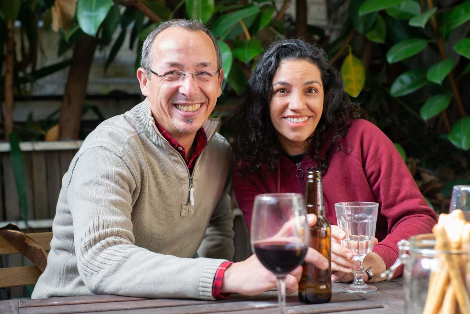 A smiling couple sharing drinks at an outdoor table
